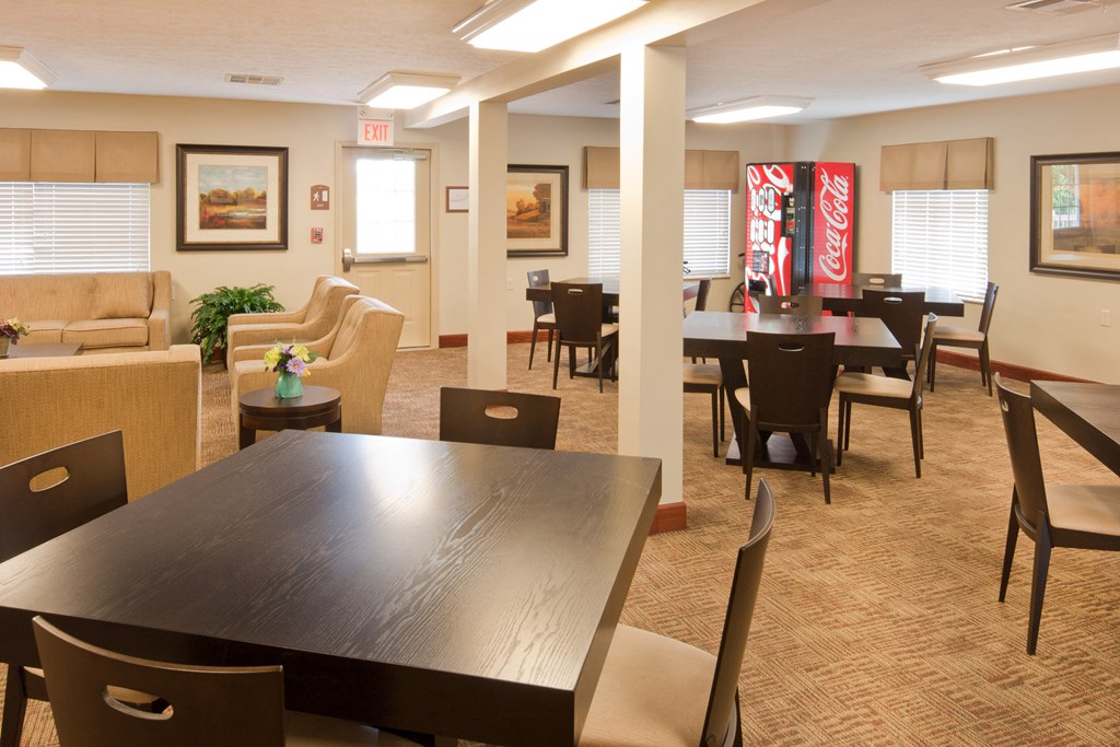a dining room with tables and chairs and a coke vending machine in a lobby