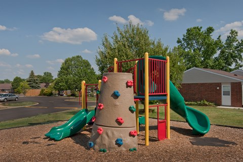 a playground with two slides and a large rock climbing wall