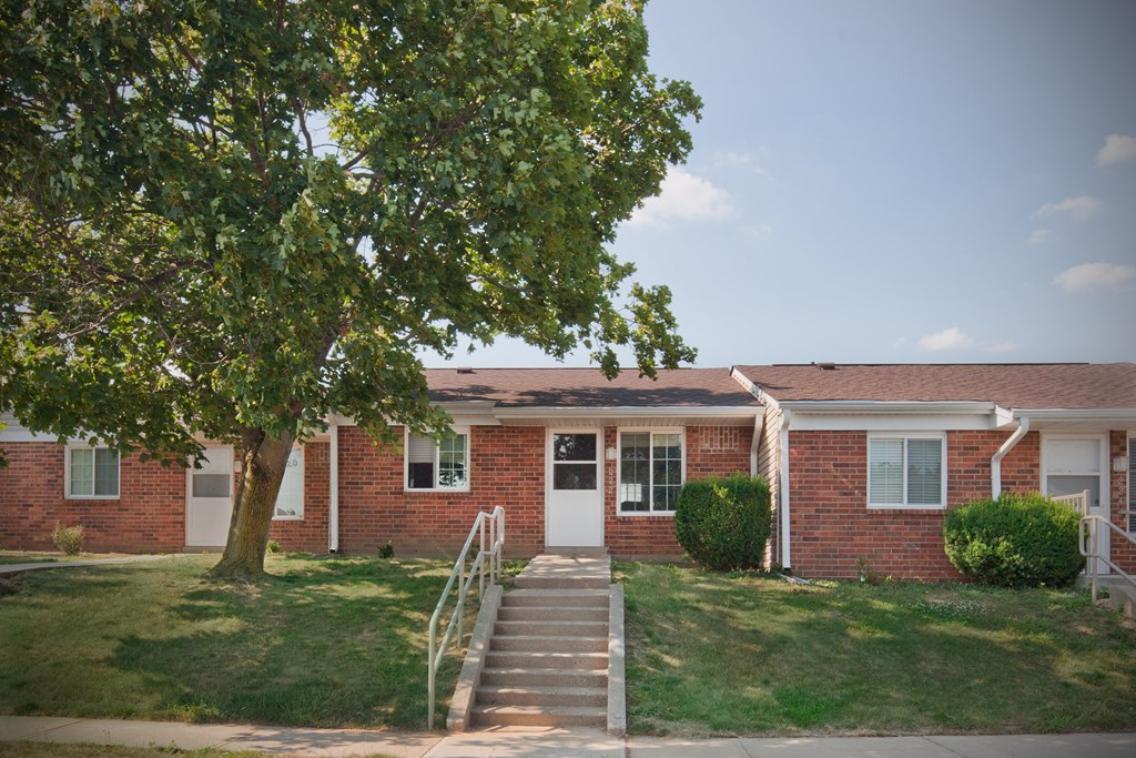 a red brick house with a tree in front of it