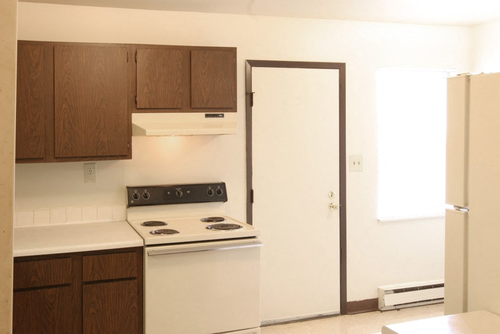 an empty kitchen with a stove and a refrigerator