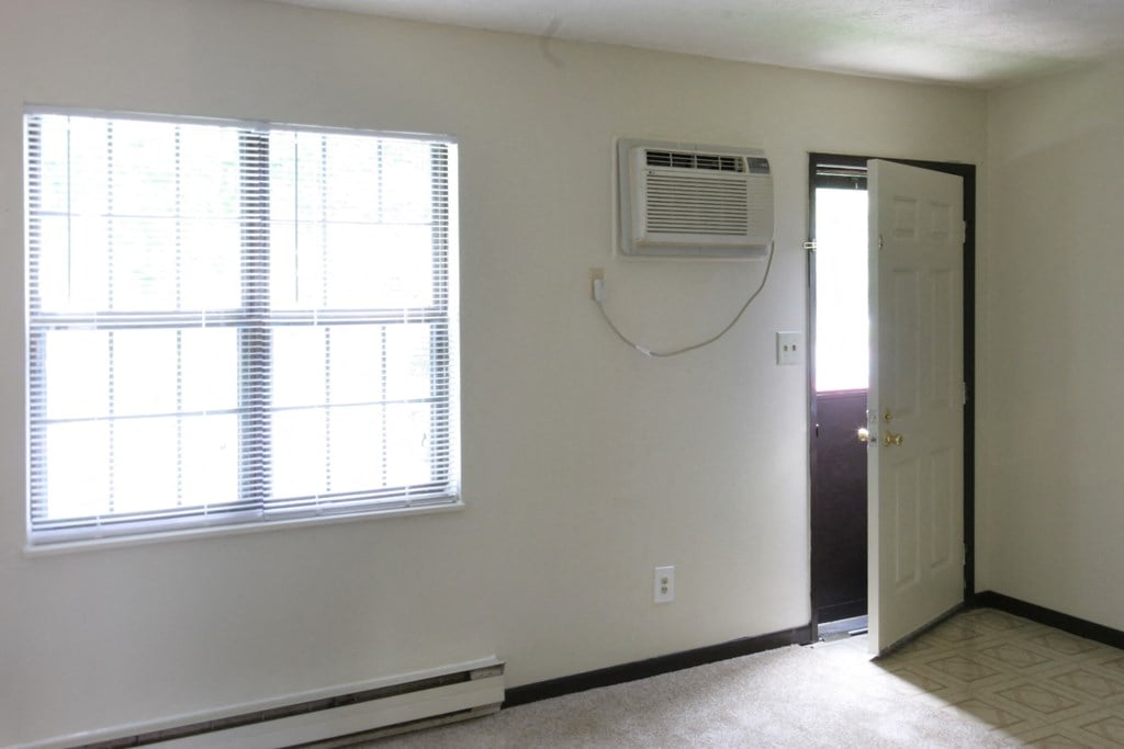 an empty room with a window and an air conditioner on the wall