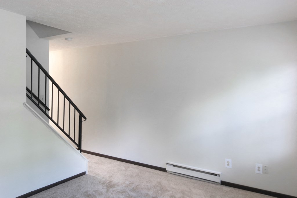 an empty living room with white walls and a staircase
