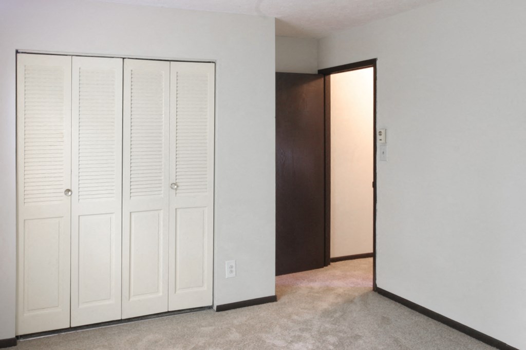 an empty room with two closets and a door to a hallway