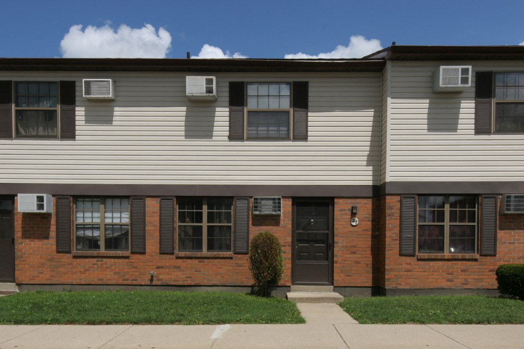 the front of an apartment building with a sidewalk and grass
