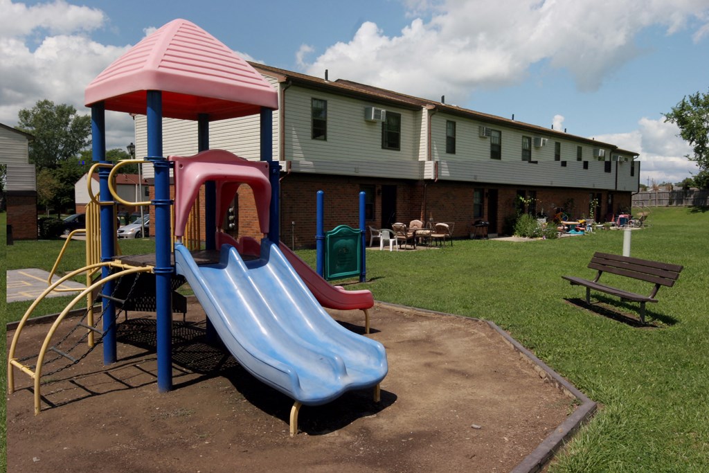 a playground with slides and a house in the background