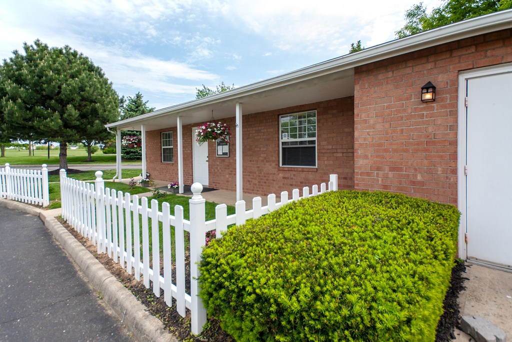 a white fence in front of a brick house