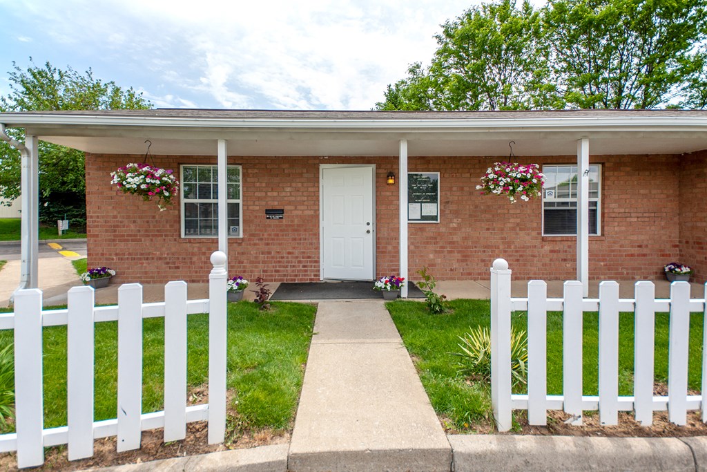 a small brick house with a white fence in front of it