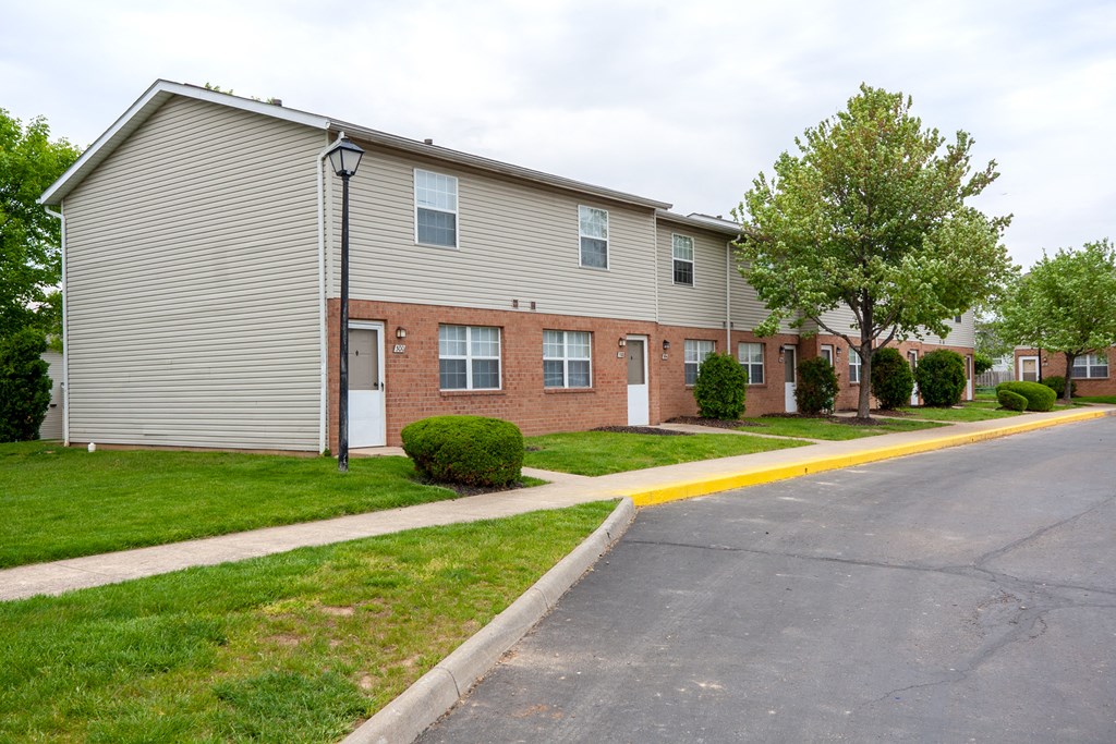 an apartment building with a sidewalk and grass