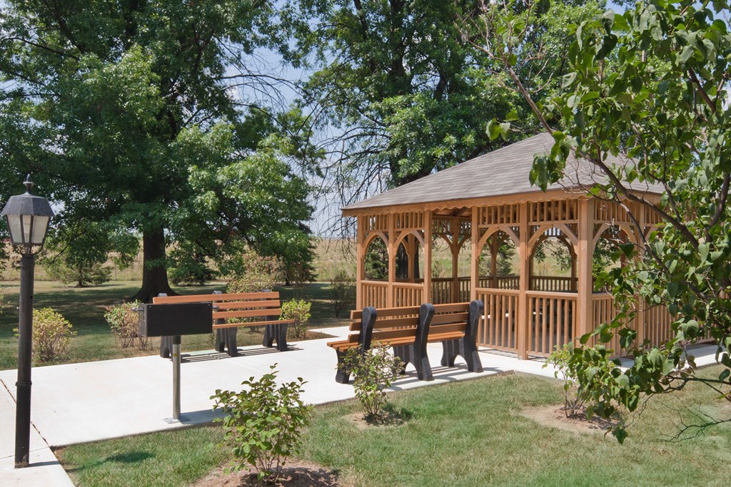 a gazebo with benches and trees in a park