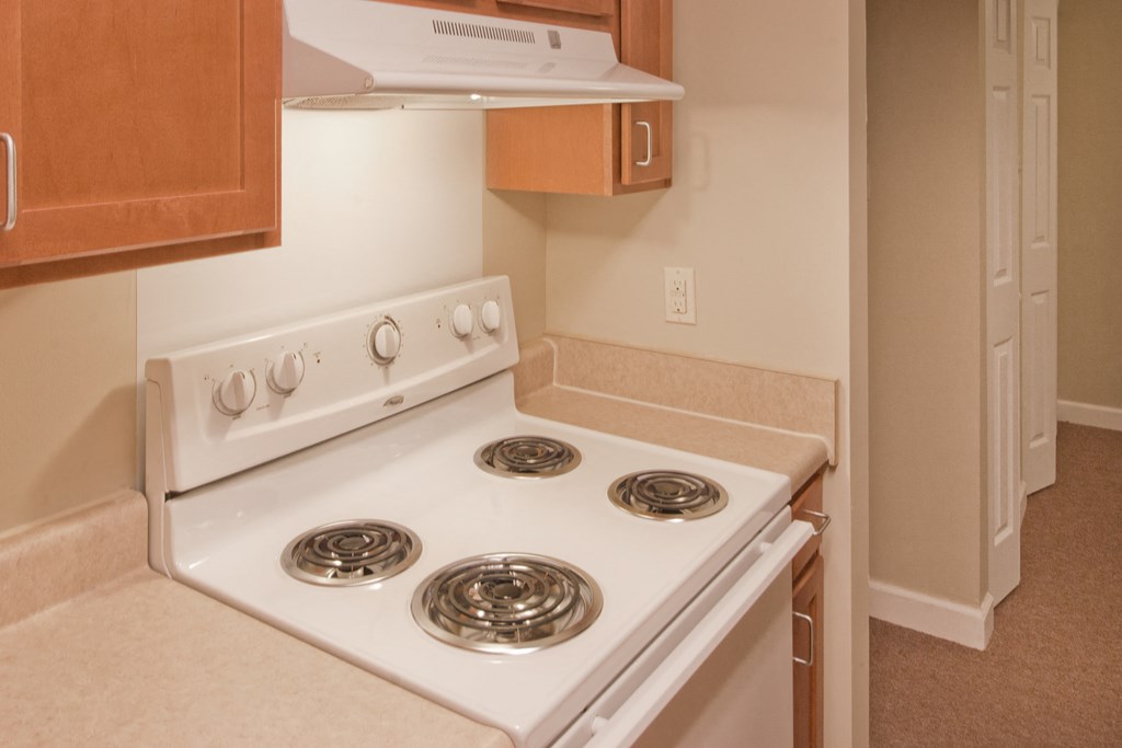 a white stove top oven in a kitchen with wooden cabinets
