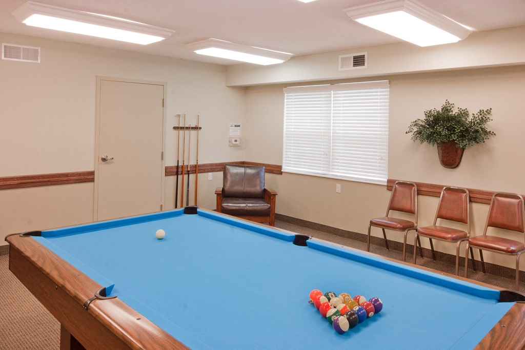 a games room with a pool table and chairs