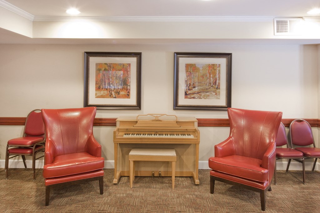 a music room with red chairs and a piano