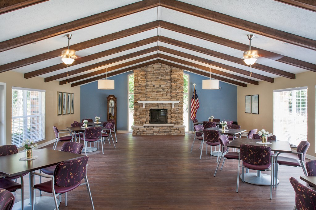 a large room with tables and chairs and a stone fireplace