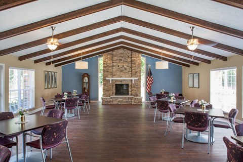 a large room with tables and chairs and a stone fireplace
