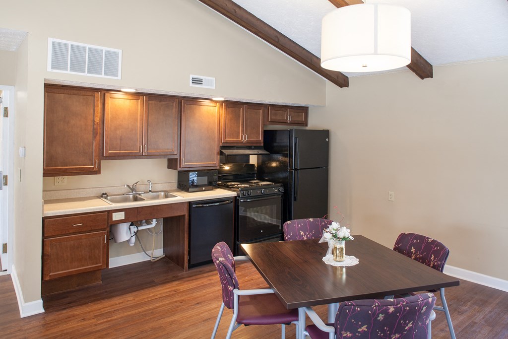 a kitchen with black appliances and a dining table with purple chairs