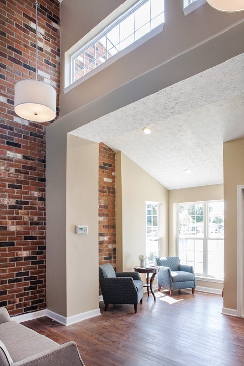 a living room with a brick wall and chairs and a table