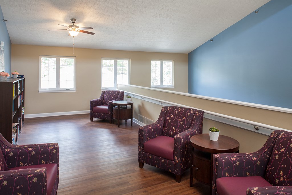 a living room with red chairs and a blue wall and a ceiling fan
