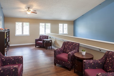 a living room with red chairs and a blue wall and a ceiling fan
