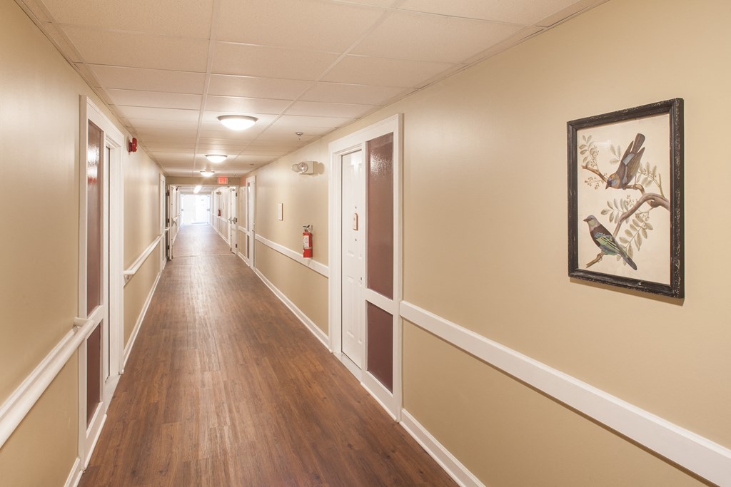 a hallway with wood floors and a painting of birds on the wall