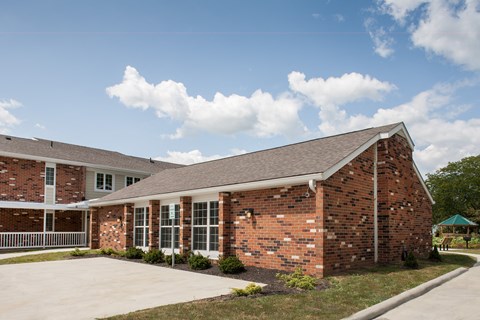 the front of a brick building with a sidewalk and grass