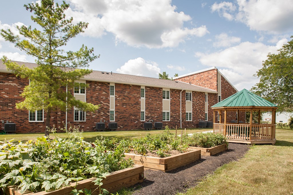 a garden with a gazebo in front of a brick building