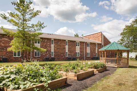 a garden with a gazebo in front of a brick building