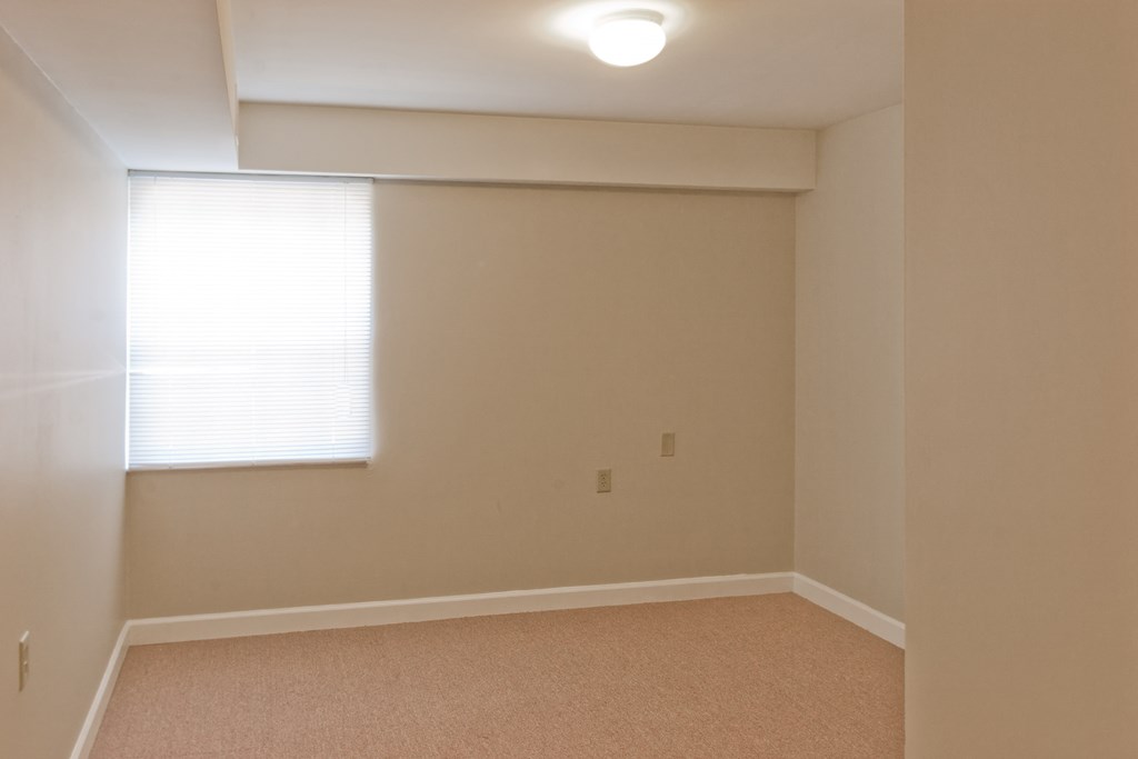 a empty room with a window and a white wall