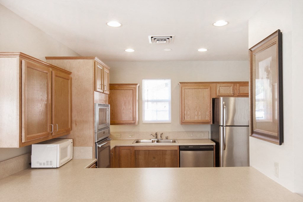 an empty kitchen with wooden cabinets and stainless steel appliances