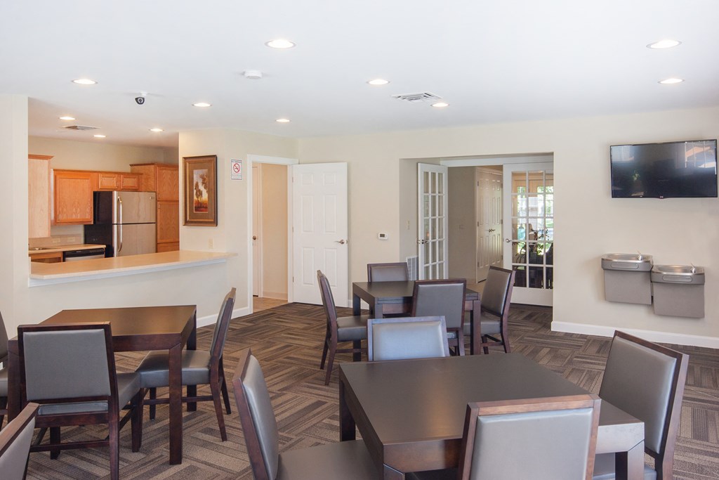 a dining room with tables and chairs and a kitchen