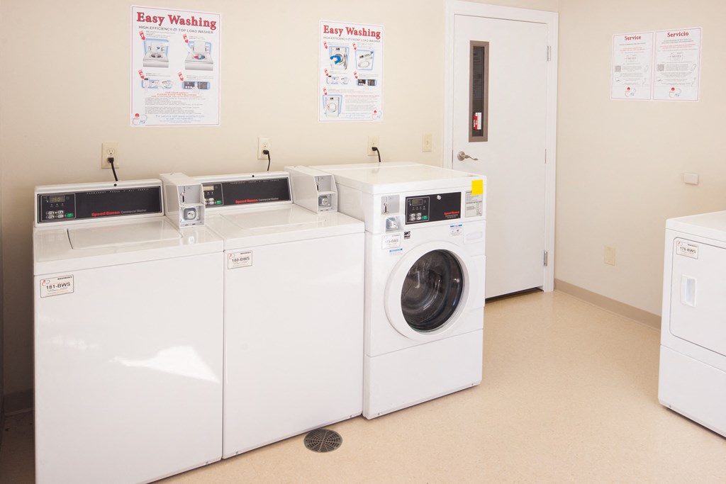 a row of washing machines and dryers in a laundry room