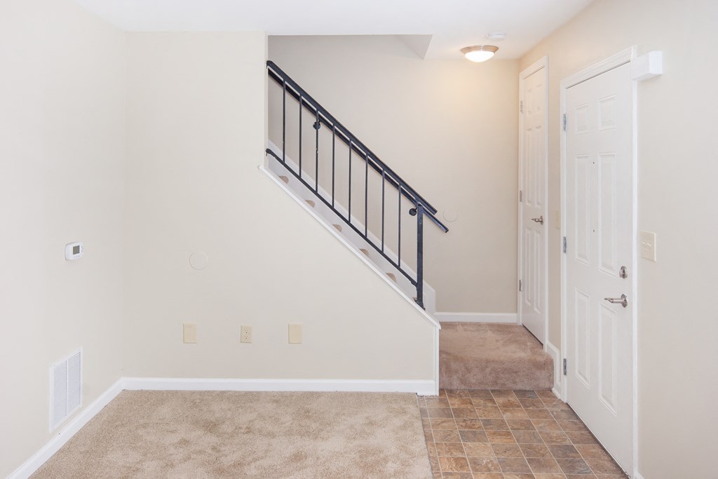 the landing of a staircase in a home with white walls and tile flooring