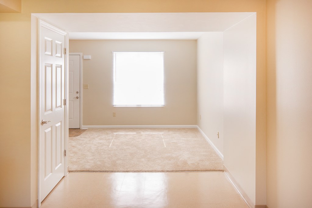 an empty room with a white door and a window