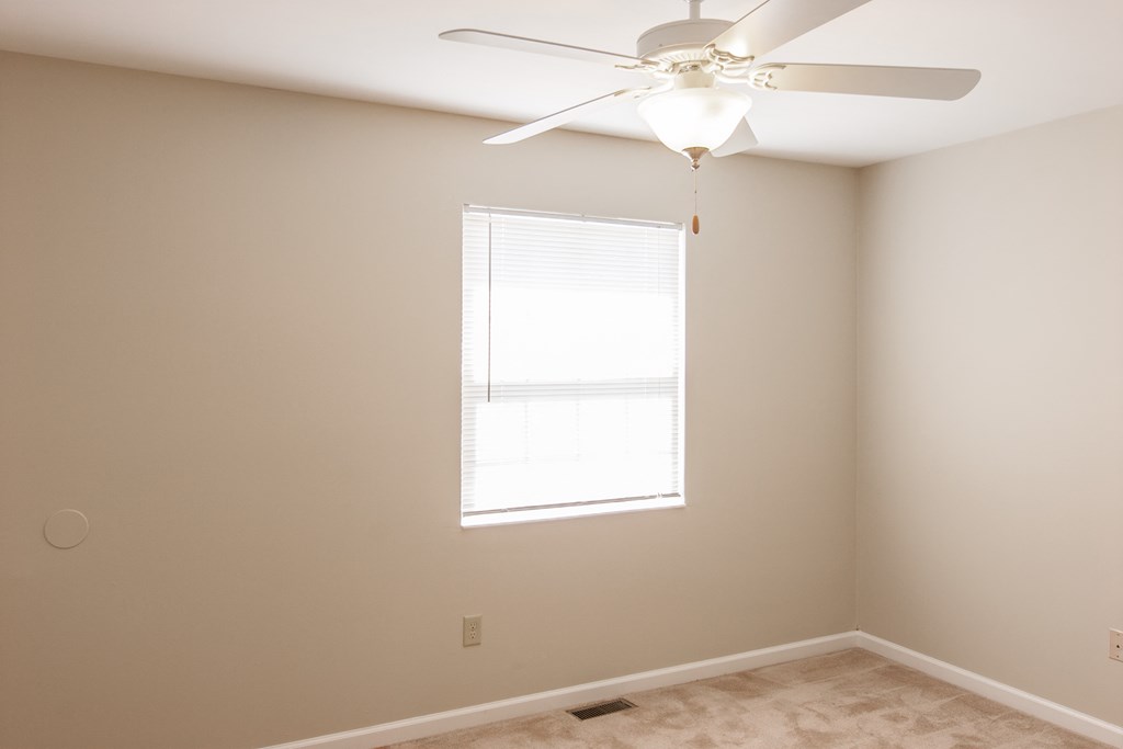 a bedroom with a ceiling fan and a window