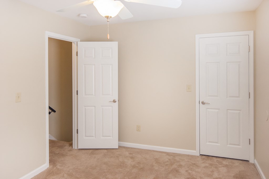 an empty bedroom with two doors and a closet