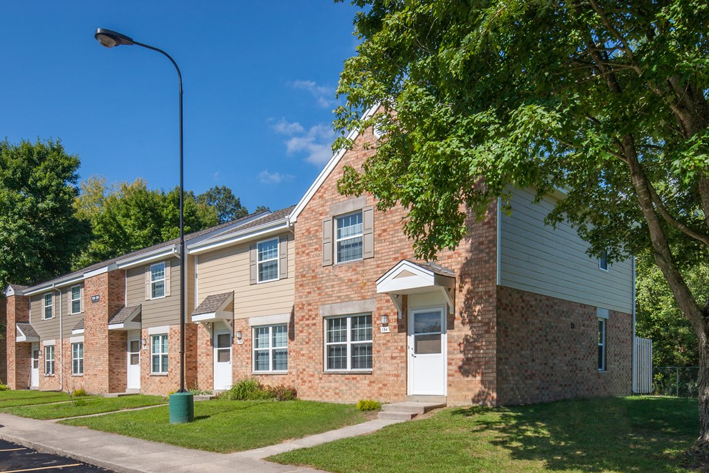 a brick apartment building with a tree in front of it