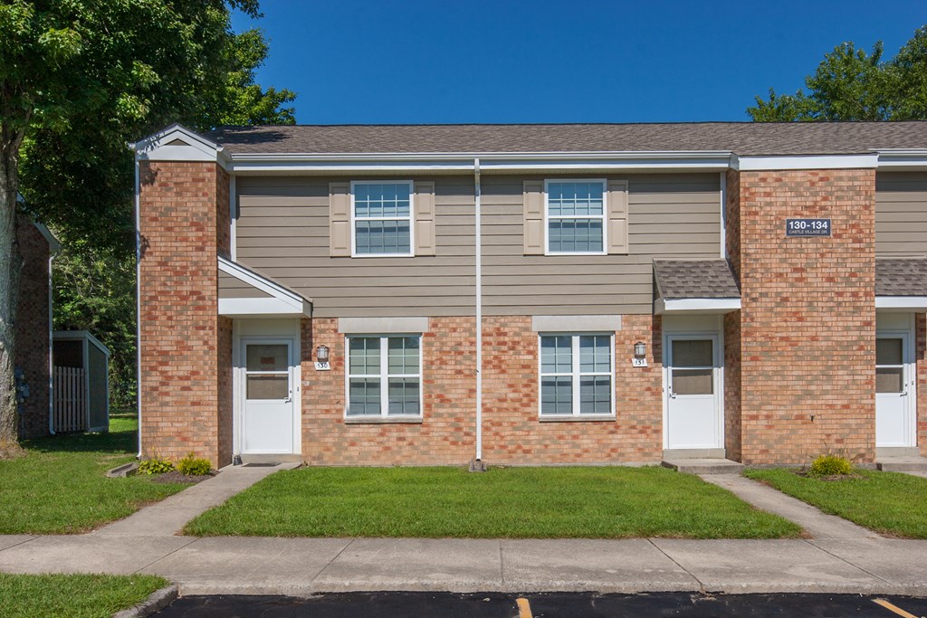a brick apartment building with white doors and a lawn