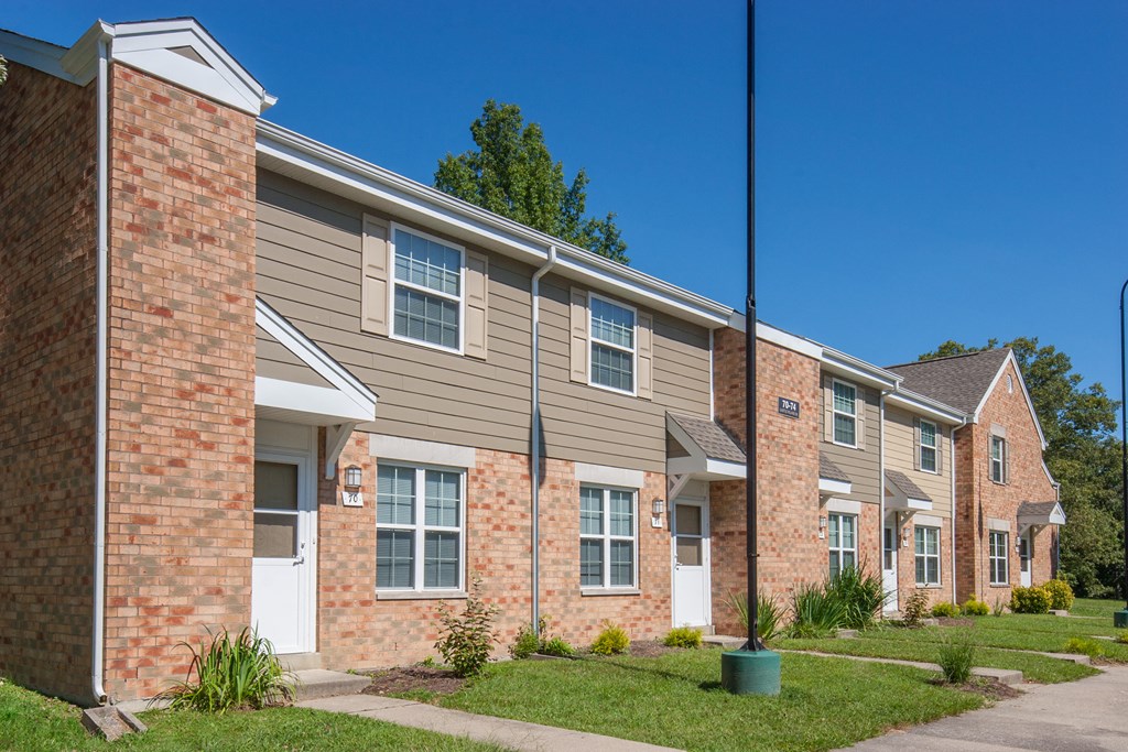 a row of brick apartment buildings with grass and a sidewalk