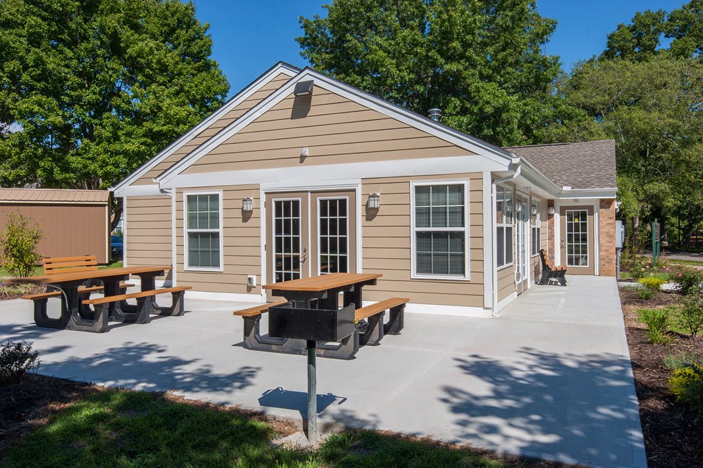 a patio with a picnic table in front of a small house