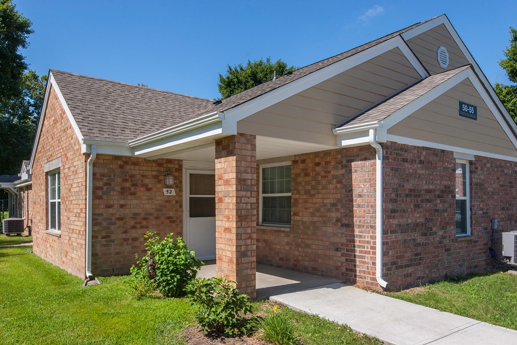 a brick house with a sidewalk in front of it