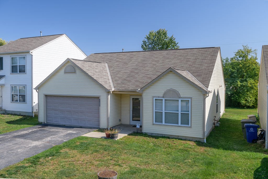 the front of a white house with a garage and a lawn