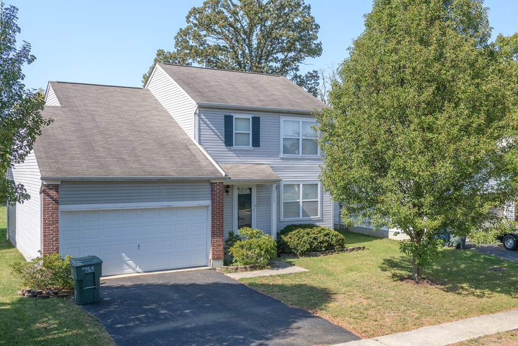 a white house with a white garage door and a tree