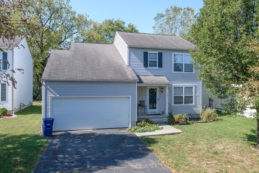 a white house with a gray roof and a blue driveway