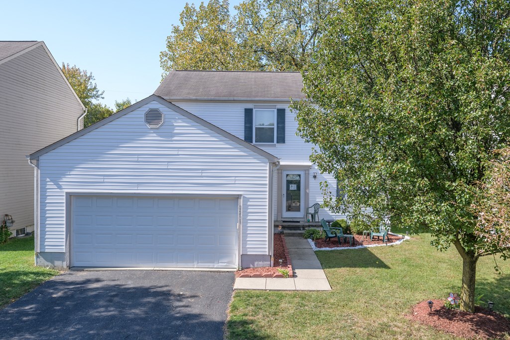 a white house with a white garage door and a tree
