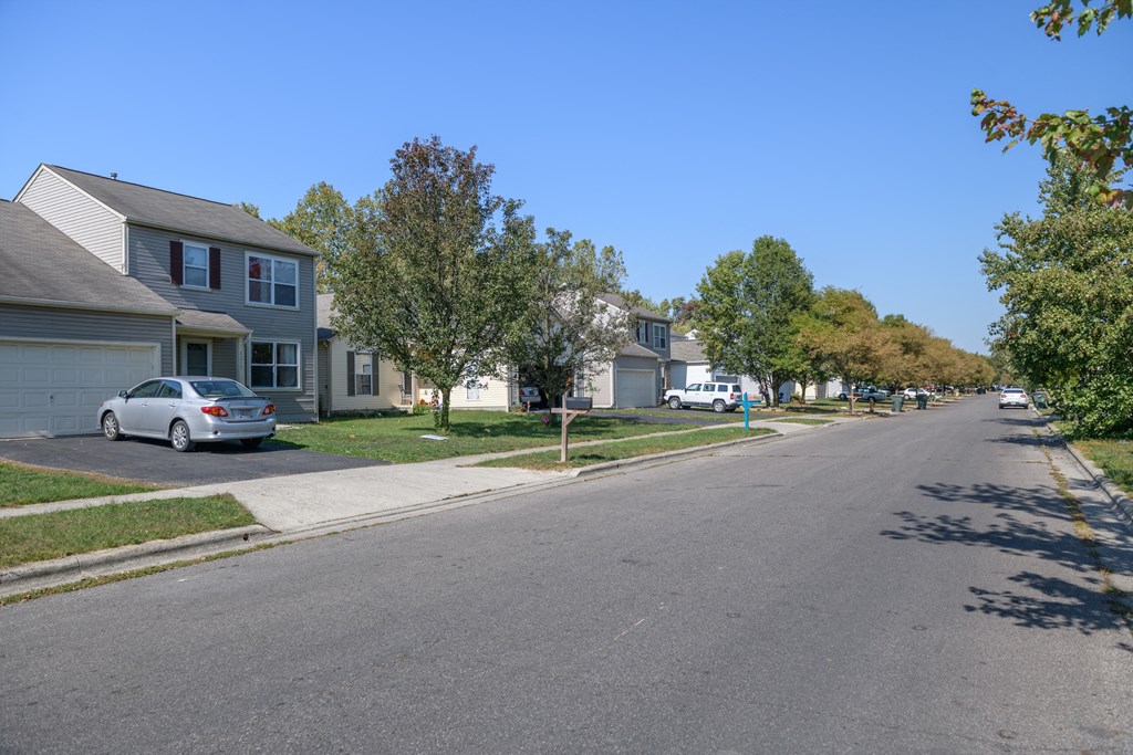 a street with houses on either side and a car parked on the curb