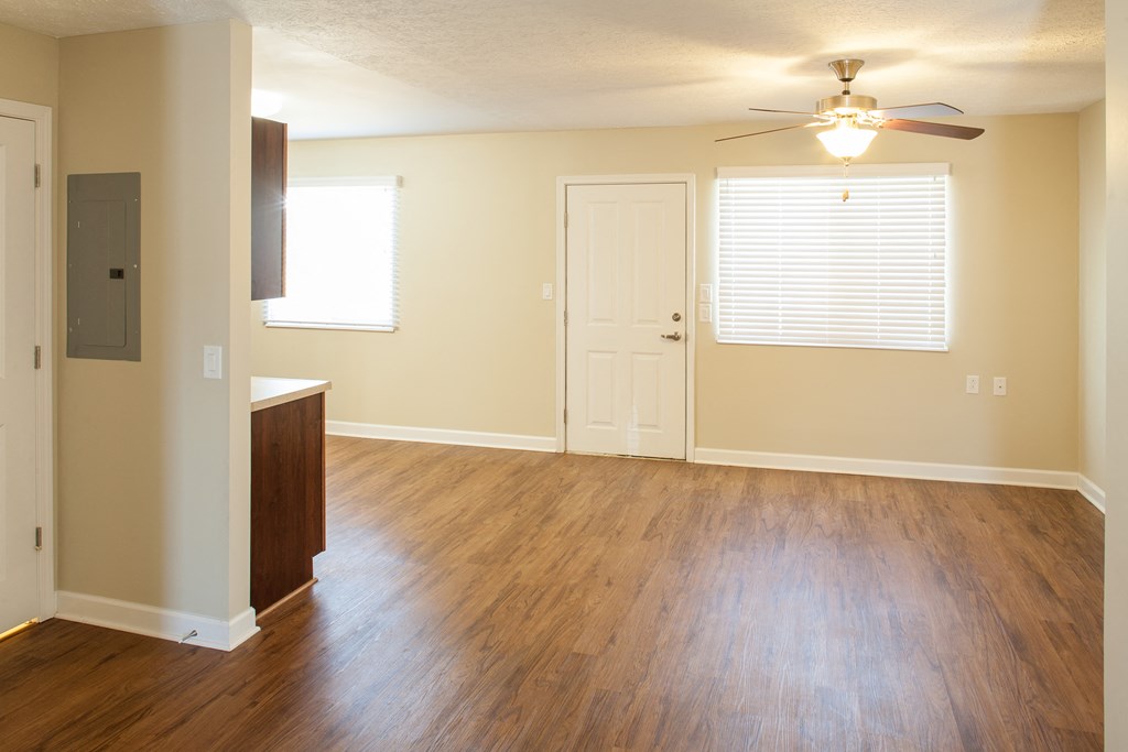 an empty living room with wood floors and a ceiling fan