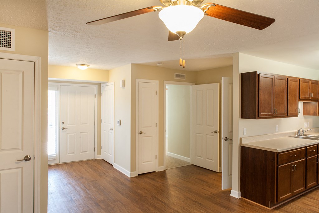 an empty kitchen with a ceiling fan and wood flooring
