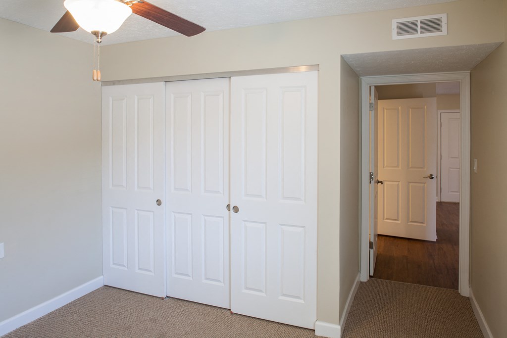 an empty bedroom with two closets and a ceiling fan