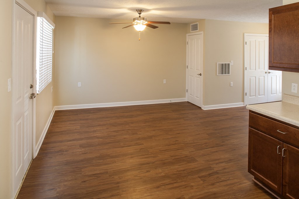 an empty kitchen and living room with wood flooring and a ceiling fan