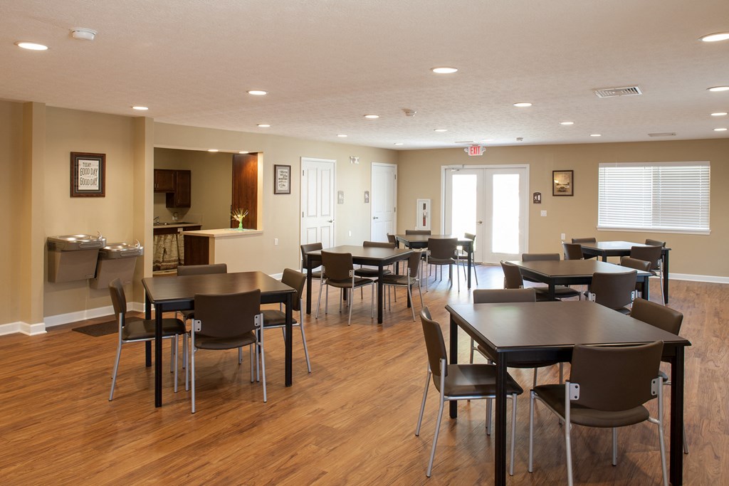 a dining room with tables and chairs and a kitchen