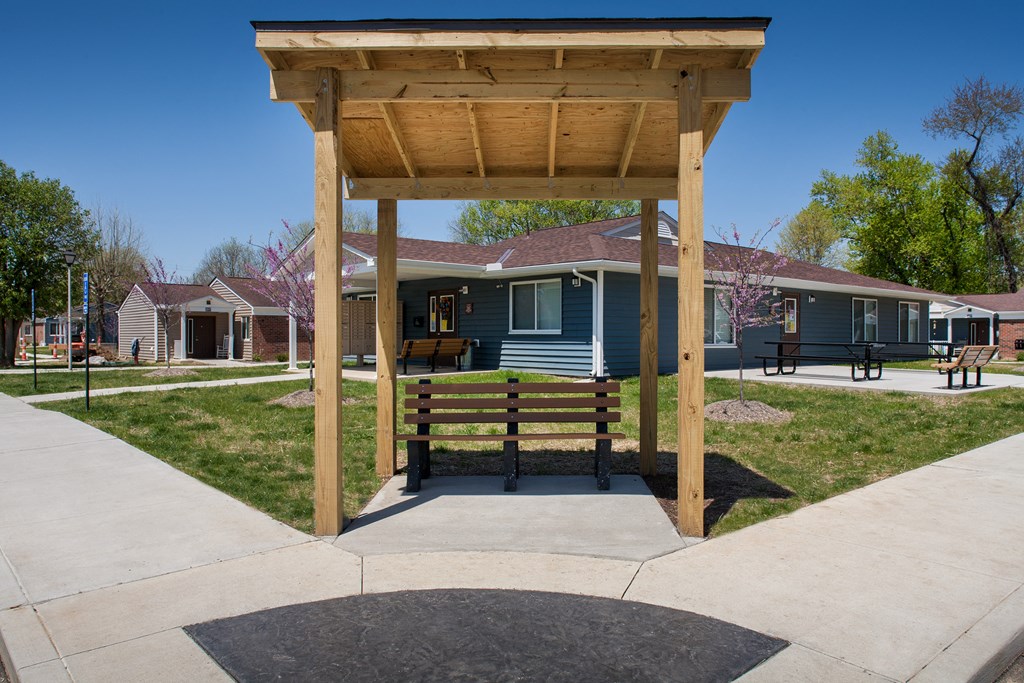 a picnic area with a wooden bench in front of a blue house